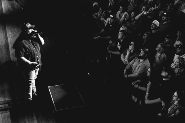 Black and white photo of luke singing, facing the crowd